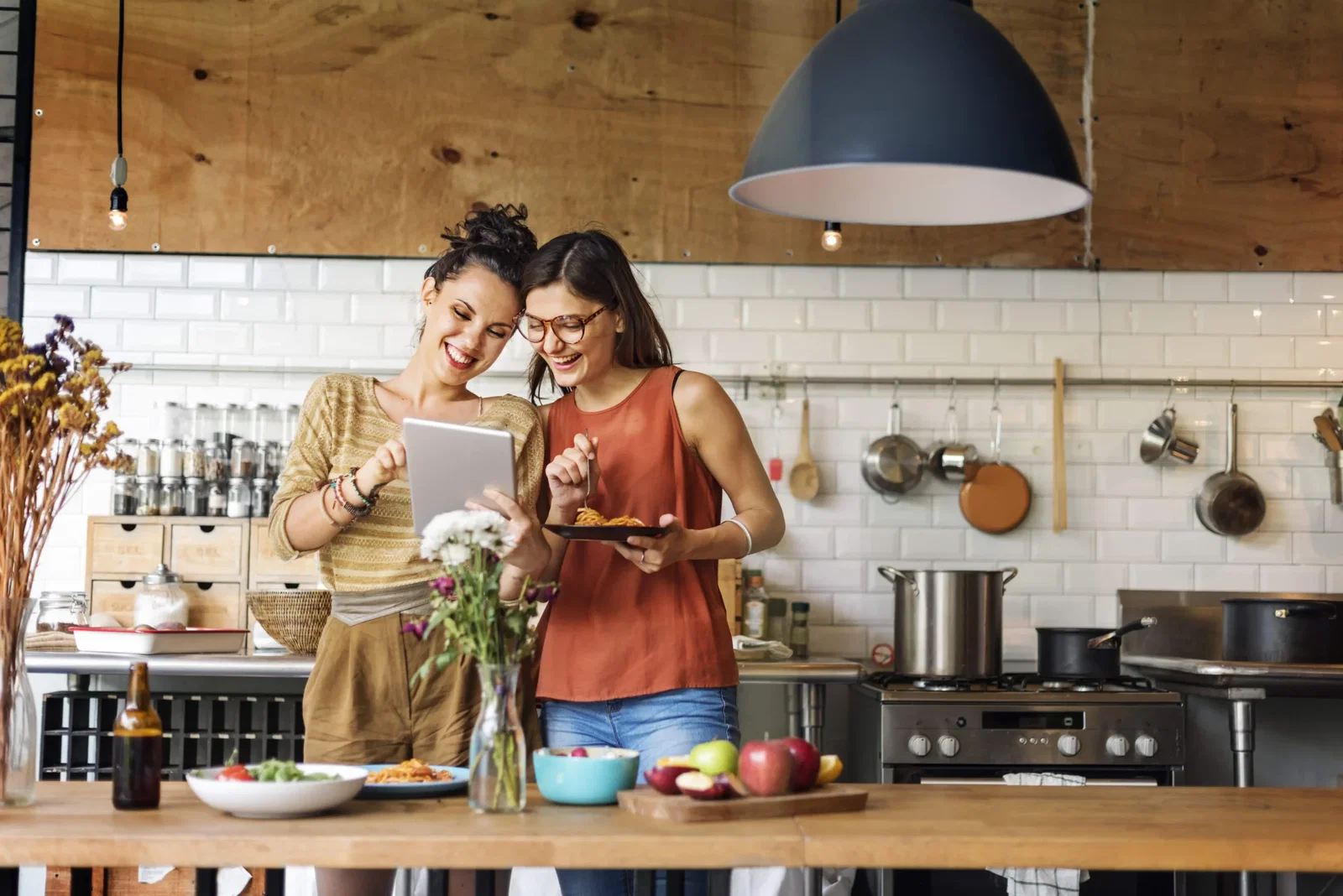 Two Girls looking at a tablet while eating